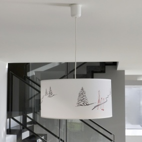 Lampada a sospensione stile montagna con motivo tracce di sci installata in un soggiorno.