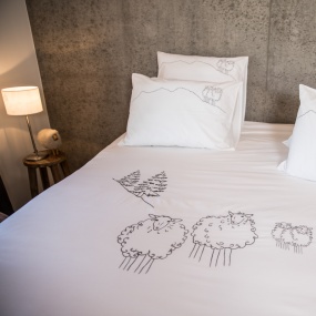White cotton percale mountain duvet cover embroidered with sheep.