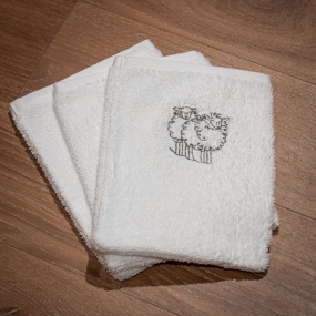 White washcloth embroidered with a grey sheep motif.