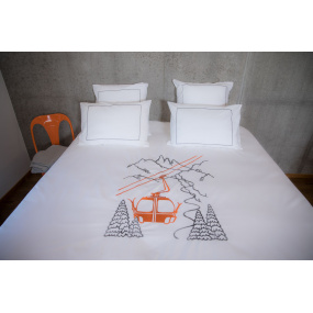 Mountain duvet cover embroidered with an orange cable car on cotton percale in a bedroom.