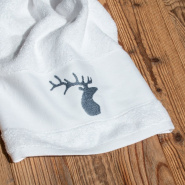 Asciugamano da bagno da montagna bianco ricamato con un motivo di cervo grigio.