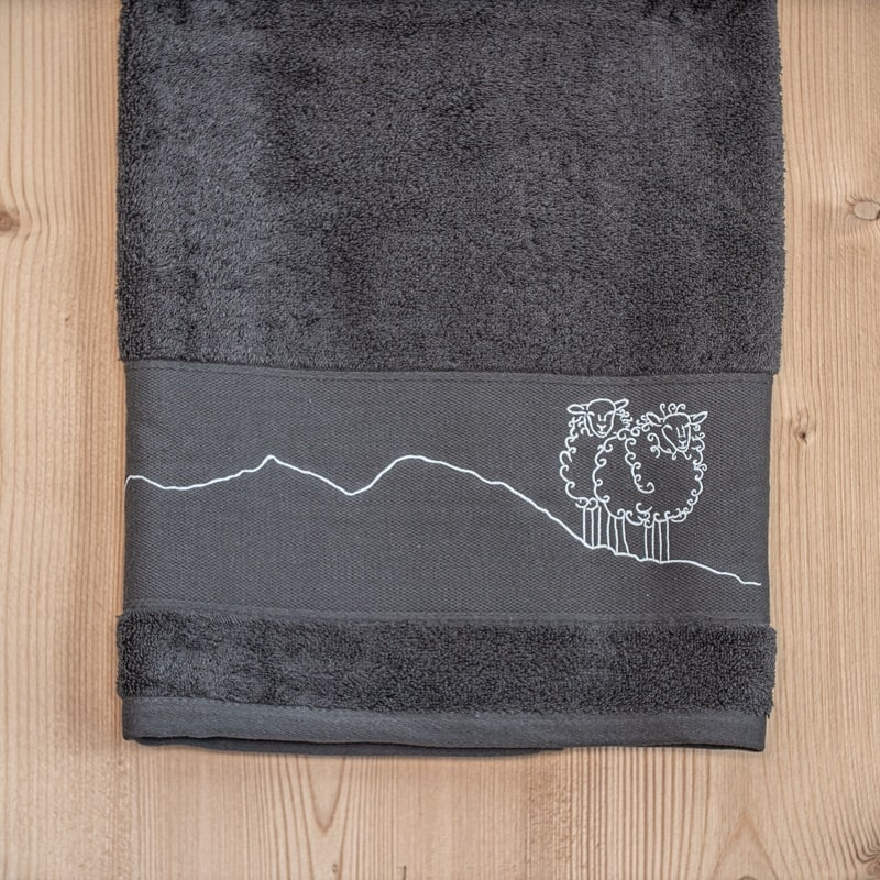 Grey mountain bath sheet embroidered with a white sheep motif.