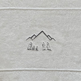 Dettaglio del ricamo marmotta sul tappetino da bagno bianco.