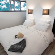 Housse de couette bord de mer brodée d'un motif sardines grises dans une chambre contemporaine.