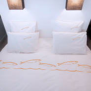 Funda de almohada de percal de algodón blanco, dispuesta sobre la cama junto con la funda nórdica a juego.