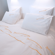 Orange fish pillowcase placed on the duvet cover from the same collection.