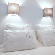 Square and rectangular sailboat pillowcases arranged on a bed.