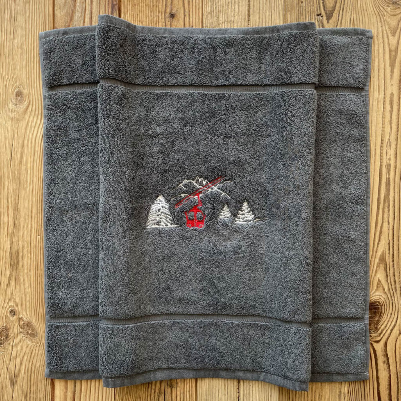 Tappetino da bagno montagna grigio ricamato con un motivo funivia rossa.