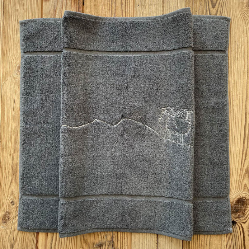 Tappetino da bagno stile montagna grigio con ricamo pecora bianca.