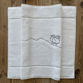 Tappetino da bagno stile montagna bianco con ricamo pecora grigia.