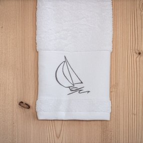 Serviette de toilette bord de mer blanche brodée d'un motif voilier gris.