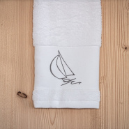 Serviette de toilette bord de mer blanche brodée d'un motif voilier gris.