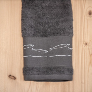 Serviette de toilette bord de mer gris brodée de motifs poissons blancs.