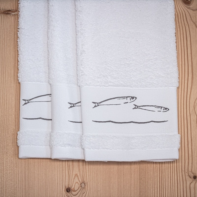 Trois essuie-mains blancs bord de mer brodés de motifs poissons gris.