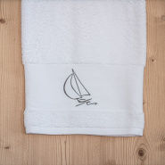Drap de bain bord de mer blanc brodé d'un motif voilier gris.
