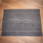 Grey coastal bath mat embroidered with white sardine motifs.