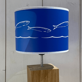 Primer plano de la pantalla de lámpara azul de estilo marinero con un motivo de sardinas.