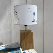 Lampada in stile marinaro a forma di faro con gabbiano, appoggiata su giornali.