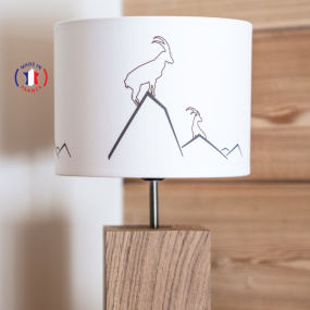Lámpara de montaña con diseño de íbice sobre fondo de madera.