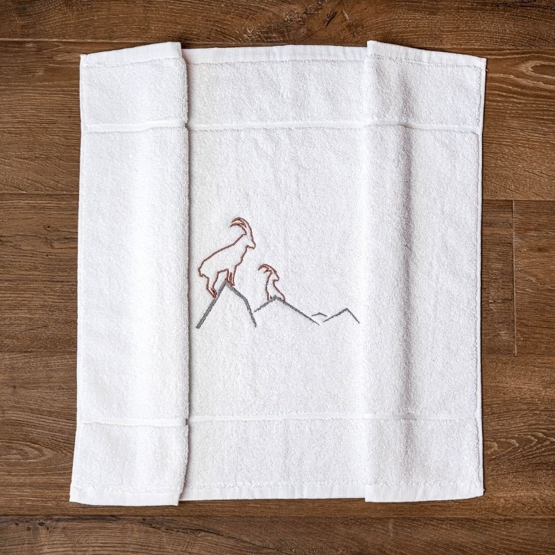 Alfombra de baño con motivos de montaña, bordada con un diseño de íbice marrón.