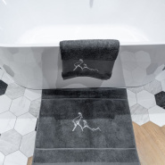 Alfombra de baño gris «bouquetin» colocada en el suelo de un cuarto de baño de un chalet.