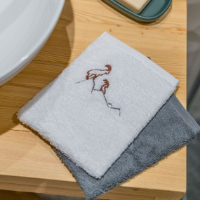 Juego de manoplas de baño con diseño de íbice en blanco y gris.