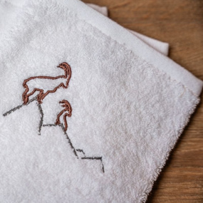 Grey and brown ibex embroidery on the white washcloth.