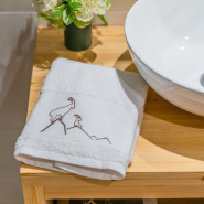 Toalla de ducha con motivos de montaña, bordada con un diseño de íbice junto a un lavabo.