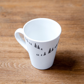 Mug bianco in ceramica stile montagna con motivi di abeti grigi.