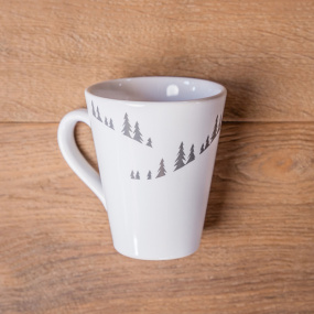 Vista dall’alto di un mug bianco in ceramica con motivi di abeti grigi.