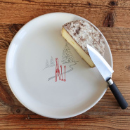 Mountain serving dish with a ski track pattern, accompanied by a piece of cheese.
