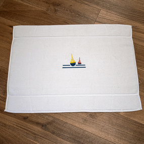 White coastal bath mat embroidered with a nautical beacon motif.