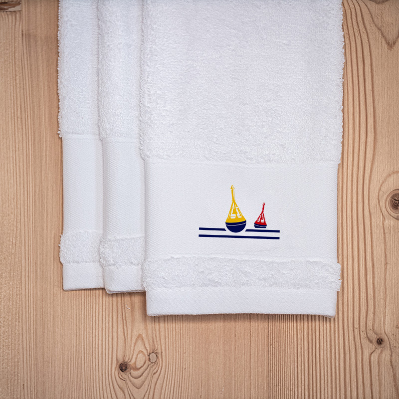 Tres toallas de mano blancas de estilo marinero, bordadas con un motivo de baliza.