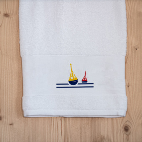 White sea-themed bath towel embroidered with a nautical beacon motif.