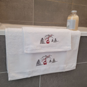 Asciugamano ospite e asciugamano da bagno funivia sul bordo di una vasca da bagno.