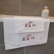 Toalla de invitado y toalla de baño «Telecabina» en el borde de una bañera.