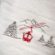 Dettaglio del ricamo del motivo funivia rossa sul telo doccia stile montagna.