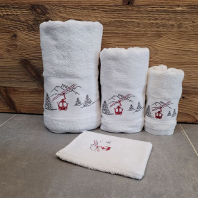 Toallas de baño blancas con motivos de montaña, bordadas con un diseño de telecabina roja.