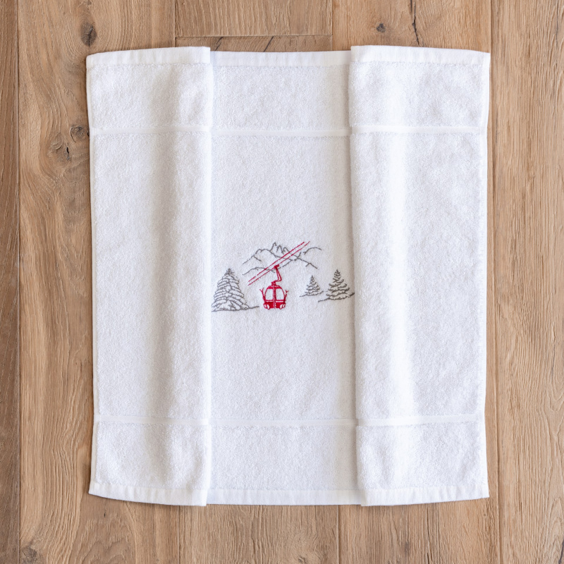Tappetino da bagno montagna bianco ricamato con un motivo funivia rossa.