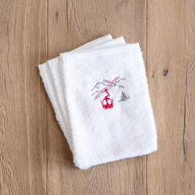 Three white mountain washcloths embroidered with a red cable car motif.