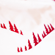 Detalle del bordado de bosque de abetos rojo en la funda de percal de algodón blanco.