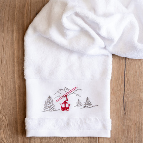 Toalla de baño con motivos de montaña, bordada con un diseño de telecabina roja.