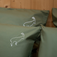 Detalle del bordado de íbice de la funda de almohada de montaña en percal de algodón verde.