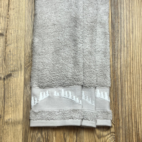 Tre asciugamani beige ricamati con un bosco di abeti bianchi.