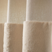Gros plan sur le détail de la fourrure et de la matière du rideau beige chalet.