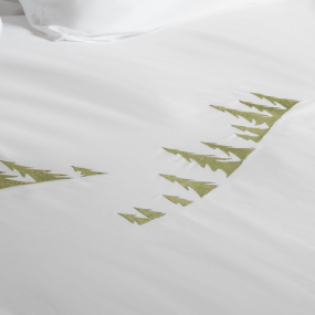Zoom sur les sapins brodées verts de la housse de couette montagne.