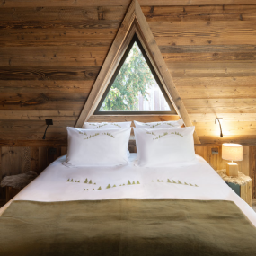 Housse de couette montagne en percale de coton blanche brodée sapins verts dans une chambre de chalet.