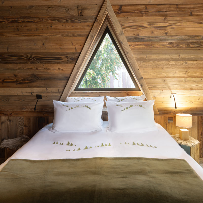 Housse de couette montagne en percale de coton blanche brodée sapins verts dans une chambre de chalet.