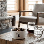 Ramequin da montagna con motivo a cervo e olive all'interno su un tavolo da chalet contemporaneo.