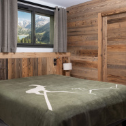 Plaid bouquetin montagne vert disposé sur un lit.